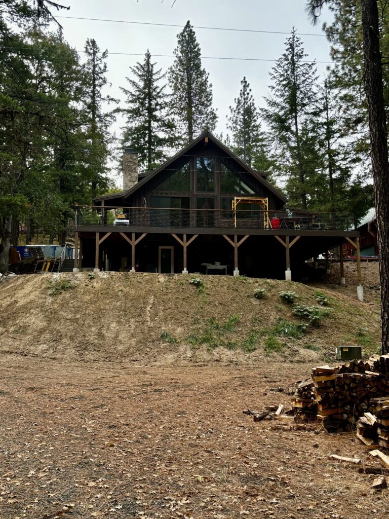 Full view of a modern timber frame cabin with a large elevated deck.
