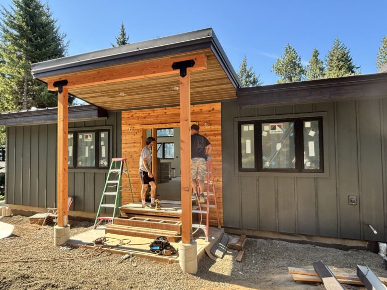 Construction workers installing a wooden porch on a modern house.