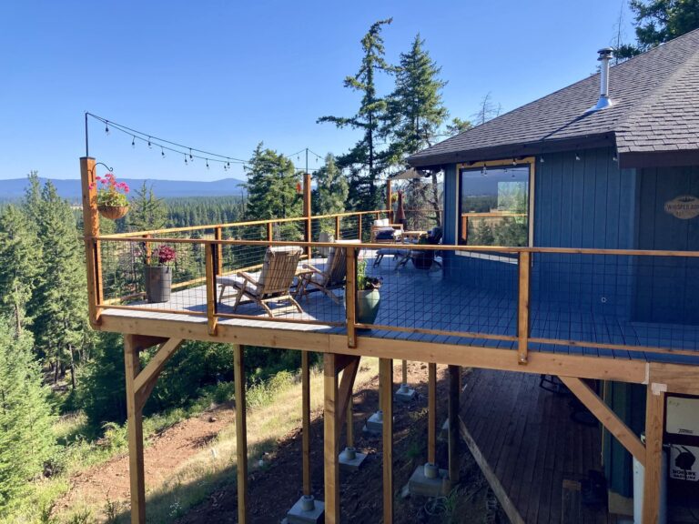 Elevated wooden deck with outdoor furniture and a forest view.