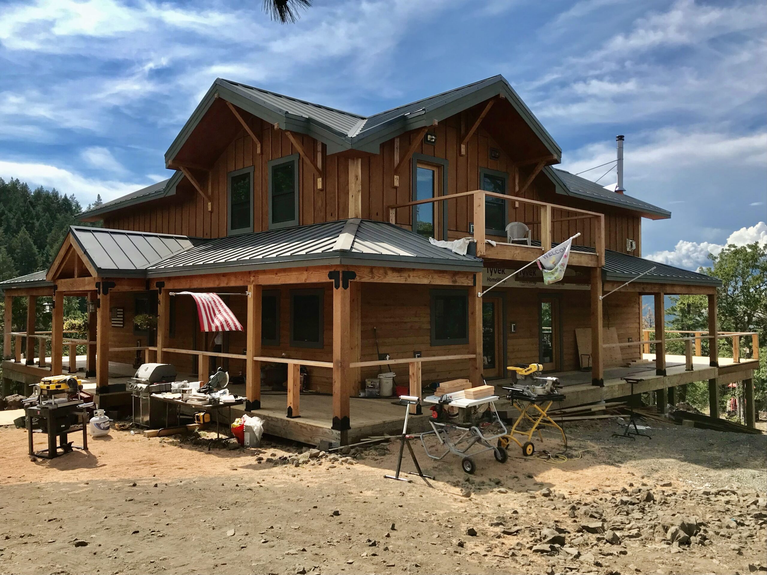 xterior of a multi-story timber frame home with a wrap-around porch and metal roof.